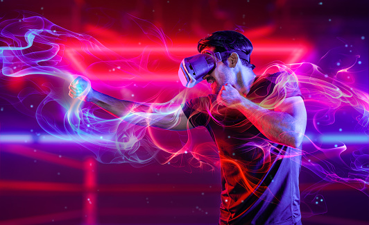 Man wearing VR glass and smashing or punching at camera in neon boxing arena. Sport gamer boxing and moving gesture in metaverse or virtual world while using digital technology innovation. Deviation.