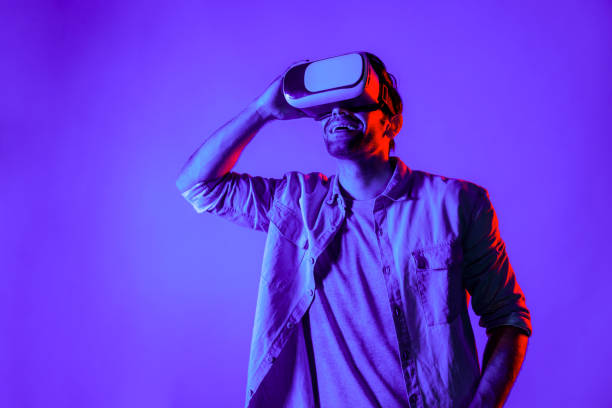 istock Smart man with VR goggles and looking at metaverse in neon light. Deviation. 2148330804