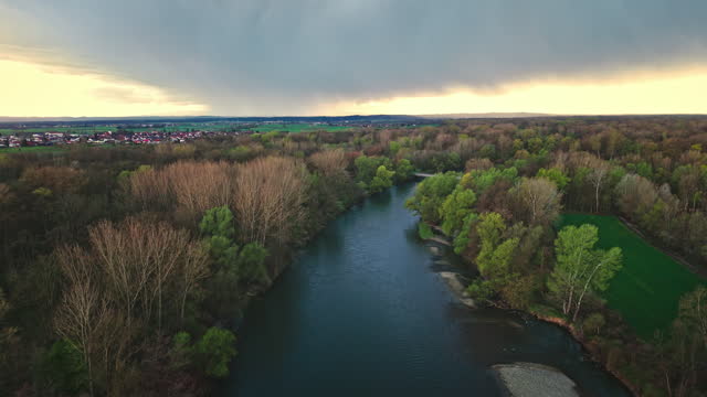 AERIAL Drone Tilt Up Shot of River Amidst Trees in Forest Under Cloudy Sky at Sunset