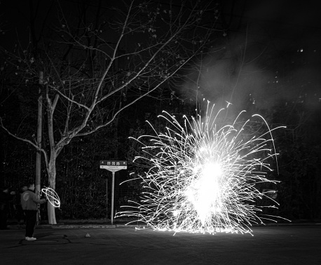 An unrecognizable child lets off fireworks next to a street sign at night in Shanghai