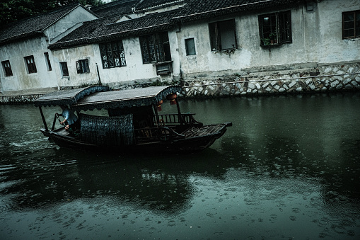 A ferryman rows through a canal past old buildings in the historical center of Suzhou
