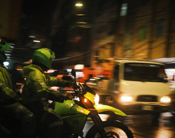 Two Medellin police officers rounding a corner in front of a white truck at night