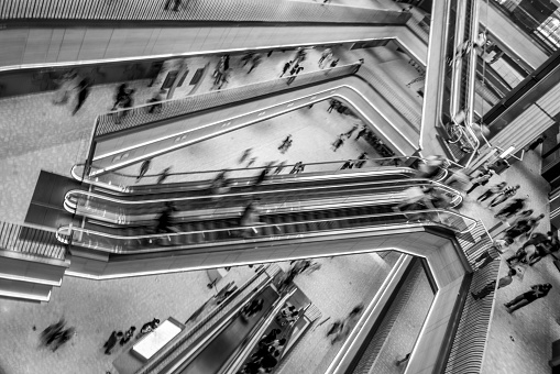 Blurred motion shot of people in a mall moving up and down multiple escalators