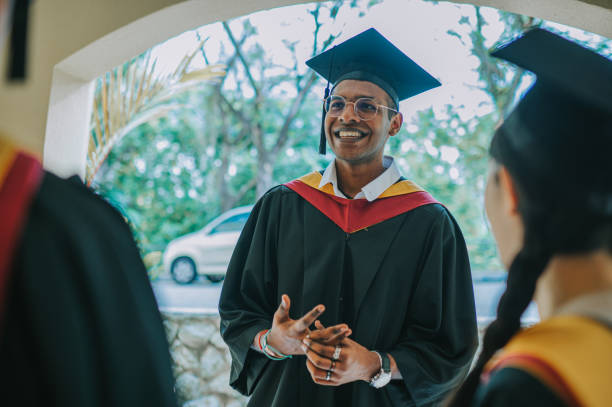 istock happy indian graduation student talking to his classmate while waiting outside of event hall 2148332086