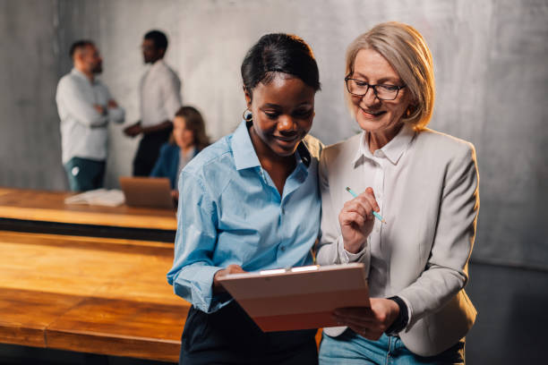 istock Multicultural businesswomen analyzing statistics on clipboard at office 2148332296