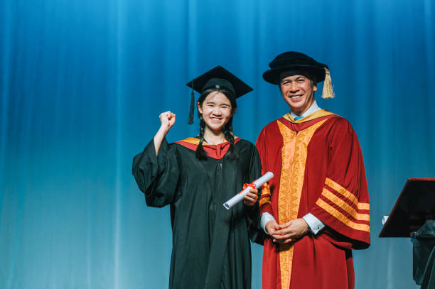 istock Convocation ceremony Excited Asian Graduation university female student arm raised standing beside Dean after received Graduation Scroll on Auditorium stage 2148332540