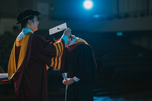 istock Asian Dean performing the turning of the tassel for university student during convocation ceremony on stage 2148332564