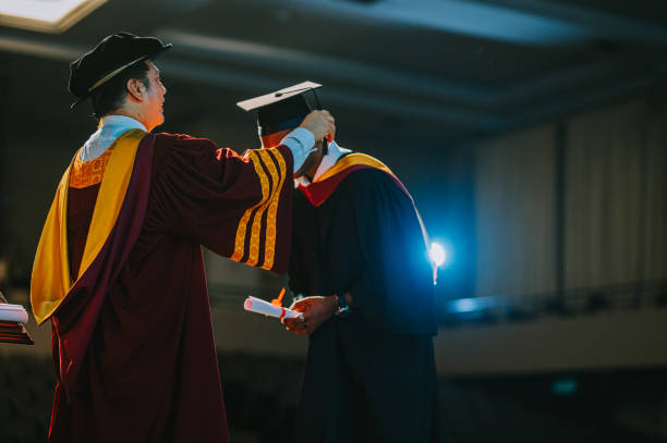 Asian Dean performing the turning of the tassel for university student during convocation ceremony on stage