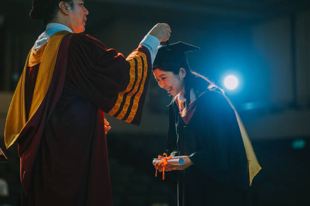istock Asian Dean performing the turning of the tassel for university student during convocation ceremony on stage 2148332583