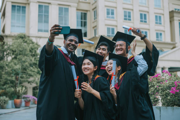 istock Asian university students in graduation gown taking selfie with smartphone with classmate 2148332653