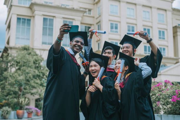 istock Asian university students in graduation gown taking selfie with smartphone with classmate 2148332669