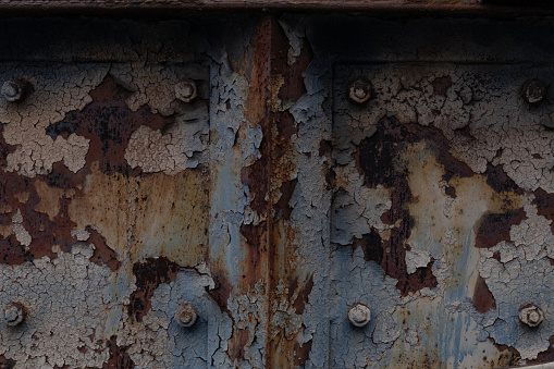Close view backdrop of rusted metal with peeling paint, patina of decay and exposure to the elements, horizontal aspect