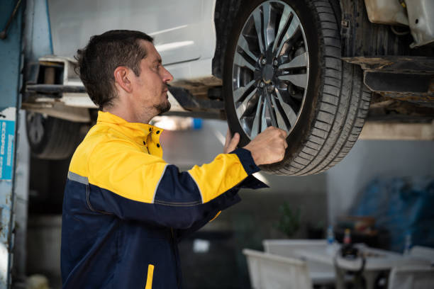 istock Hardworking mechanic changing car wheel in auto repair workshop. Oxus 2148335836