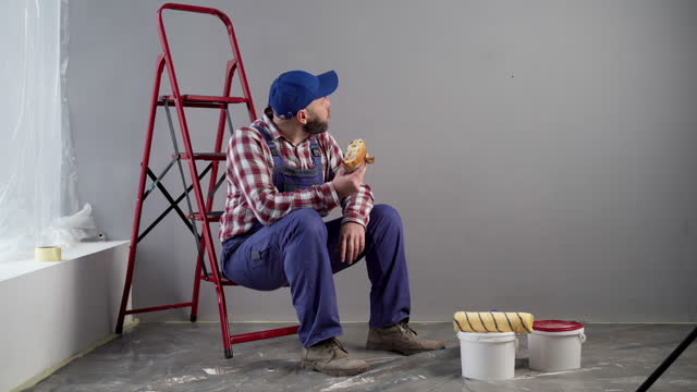 Painter eating burger at work. Fast food delivery concept