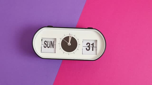 Alarm clock with the time and date of Easter on a lilac-pink background.