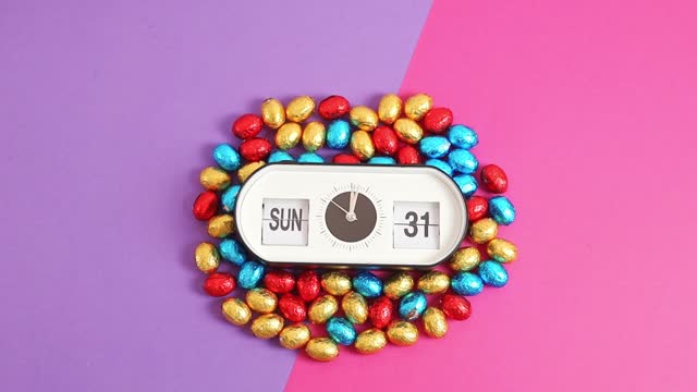 Alarm clock with Easter time and date and Easter eggs on lilac pink.