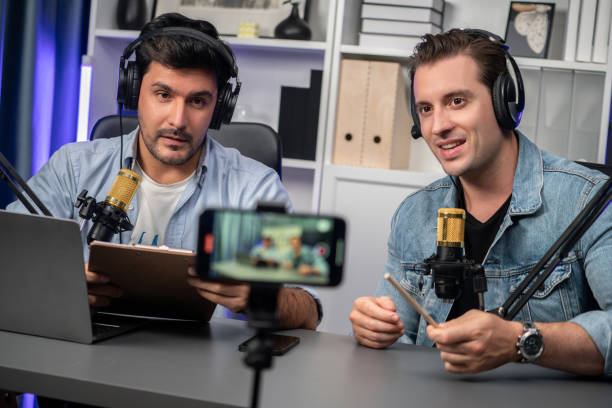 istock Host channel of creative broadcaster living by smartphone with guest. Sellable. 2148338040