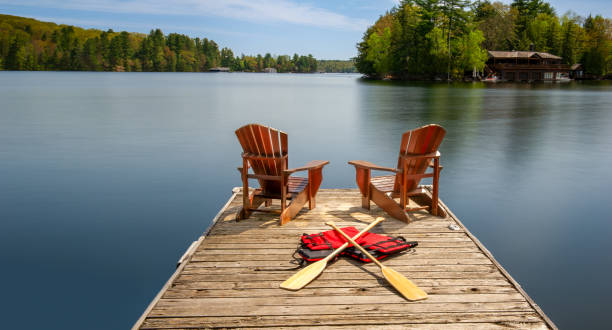 istock Two Adirondack chairs on a dock with canoe paddles and life jackets 2148342887