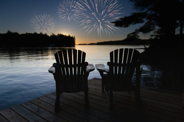 Celebratory fireworks above two Adirondack chairs on the dock