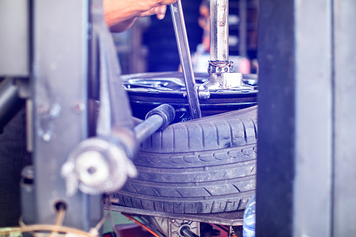 Selective focus to machine do removing car tires from wheel rims. Dismantling tire from rim using special machinery. Car service center.