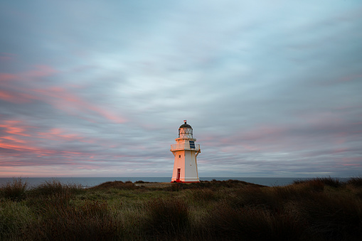 Early in the morning on a cloudy day at the Waipapa Point Lighthouse, a break in the cloud on the eastern horizon allows the warm glow of dawn to shine through, lighting up the lighthouse and some of the clouds.
The lighthouse is located in the Catlins area, on the south coast of New Zealand's South Island, east of Invercargill. It was built after the wreck of a passenger steamer cost 131 lives and was first lit on 1st January 1884. It was one of the last wooden lighthouses to be built in New Zealand and is a popular tourist destination for visitors to the area.
