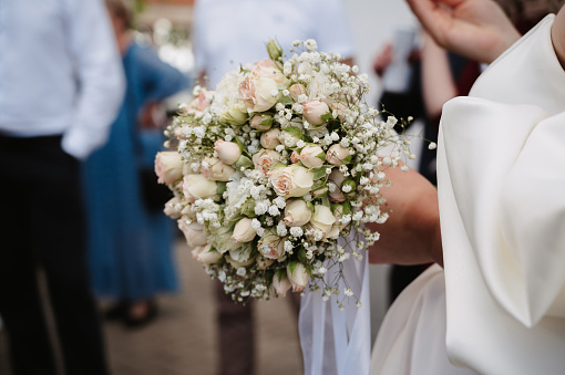 wedding bouquet of white roses in the hands of the bride on the wedding day