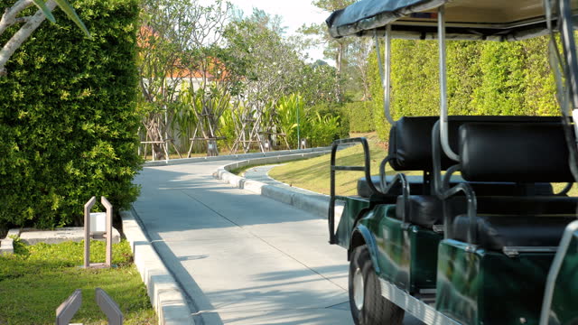 Golf cart with passenger driving along scenic path in lush green resort