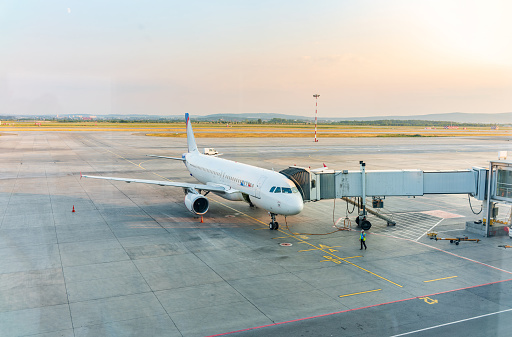 Passenger plane on the airfield connected to walkway.The gate sleeve is docked to the aircraft.