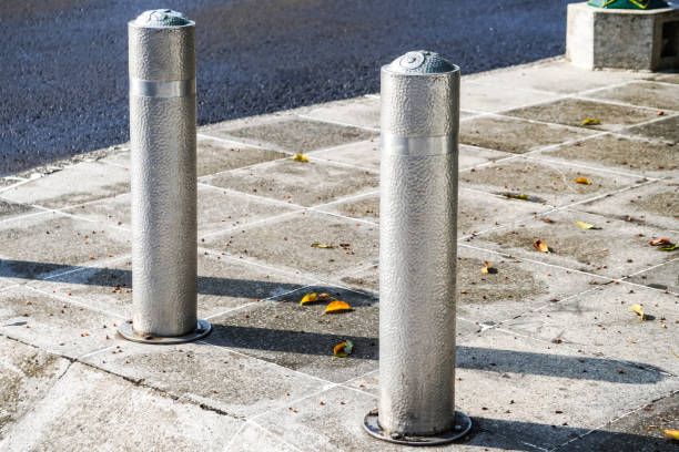 istock Metallic long inground bollard pole barrier between asphalt road and sidewalk to protect pedestrians and roadside decoration. Town square, urban, city, infrastructure. In Ground Metal Bolard. 2148351728