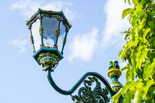 Typical street lamp from Yogyakarta. Classic Javanese green framed glass lamp against bright blue sky background. Empty blank copy text space.