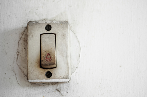 Old worn electronic house bell switches with white background, switches on weathered white wall. doorbell, home electrical switch.