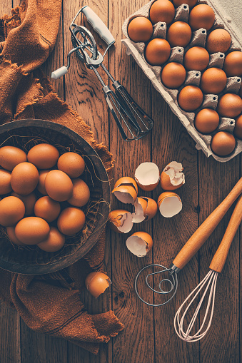 Fresh organic eggs with kitchen and baking utensils on wooden table