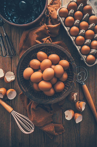 Fresh organic eggs with kitchen and baking utensils on wooden table