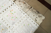Close up photo of textured white tablecloth with floral designs used to cover an old wooden table.