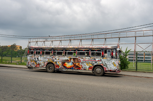 Galle, Sri Lanka - January 29, 2024: A colorful graffiti-covered bus parked near the historic Galle Dutch Fort under a cloudy sky.