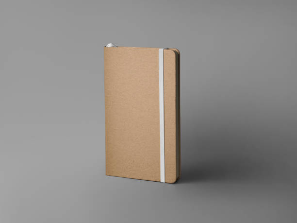 istock Mockup of closed craft notebook, standing on background with shadows, with white elastic band, bookmark, textured hard cover. 2148354689