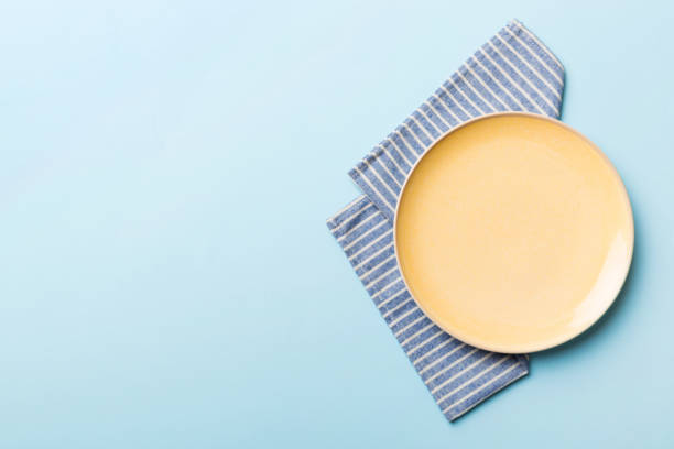 istock Top view on colored background empty round yellow plate on tablecloth for food. Empty dish on napkin with space for your design 2148354799