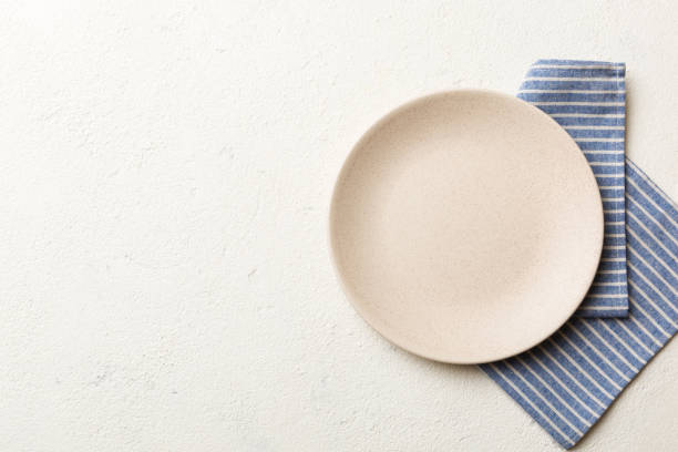 Top view on colored background empty round white plate on tablecloth for food. Empty dish on napkin with space for your design Top view on colored background empty round white plate on tablecloth for food. Empty dish on napkin with space for your design. empty plate stock pictures, royalty-free photos & images