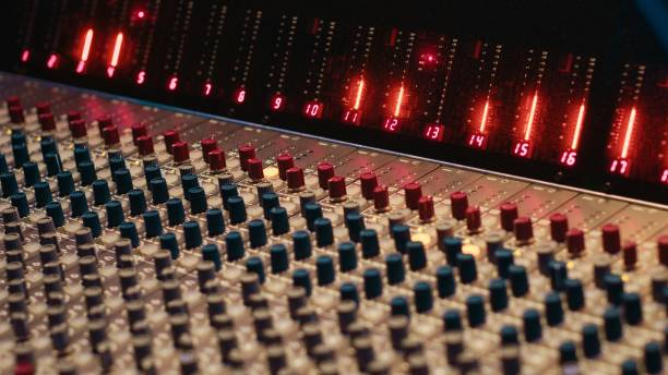 Control room desk equipped with motorized faders and amplifier used in mixing and mastering tracks with audio console. Empty soundproof studio with sliders and switchers on board.