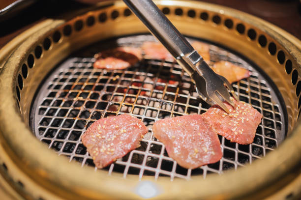 Portrait Asian familyGrilling best beef japanese style restaurant and putting raw beef slices over the charcoal grill stove