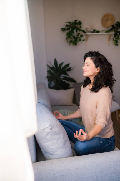 istock Woman takes a deep breath while meditating on the sofa at home 2148356718