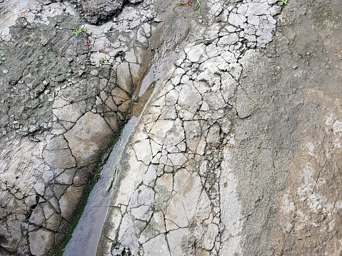 a photography of a small stream of water running through a cracky rock.