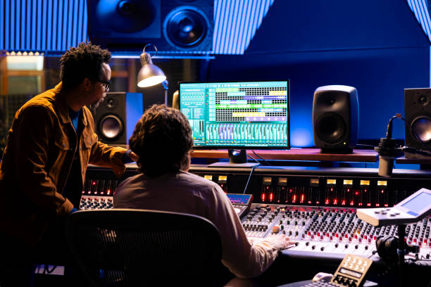 istock Singer and producer work on soundboard controller at recording studio station 2148357002