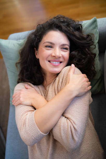 istock Happy woman feels beautiful while lying on the couch at home 2148357309