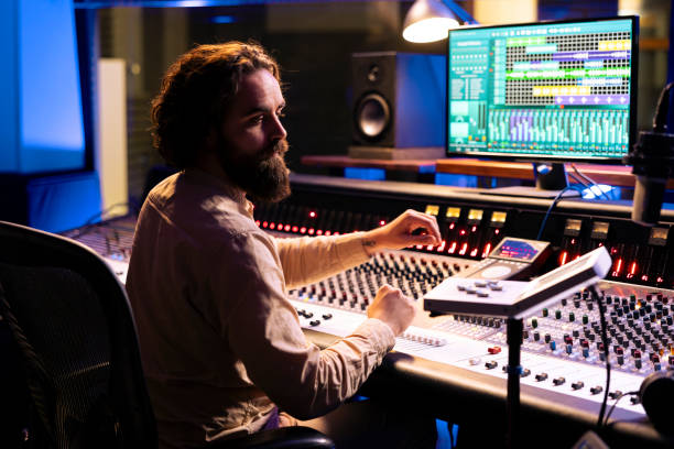 istock Music technician mixing and mastering songs with motorized faders and knobs 2148357638