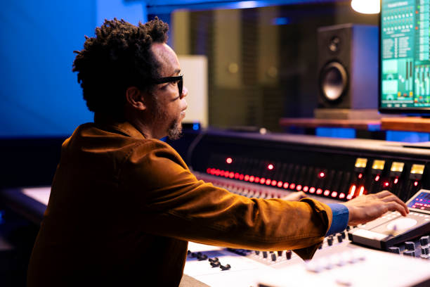 istock African american record producer adjusting sound settings on control board desk 2148357817
