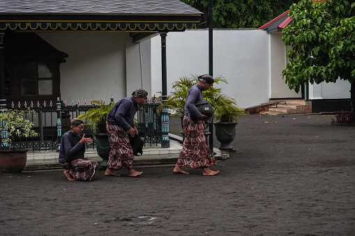 Jogja, Indonesia - January 31, 2024: Male Abdi Dalem or servants of Sultan of Yogyakarta walked while kneeling making respectful gestures when entering the palace area.