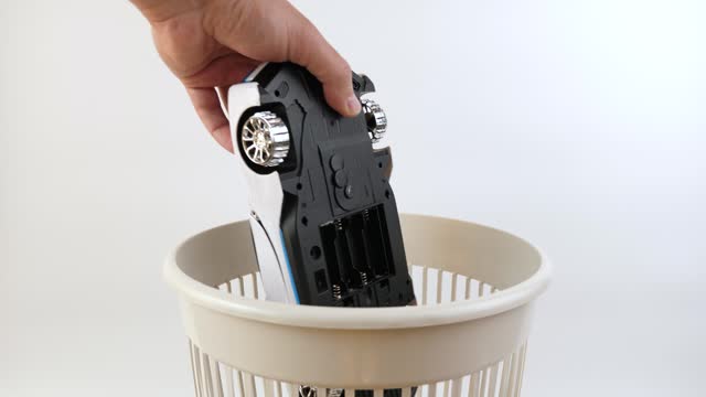 A broken children's toy car is thrown into the garbage can. Recycling of plastics.