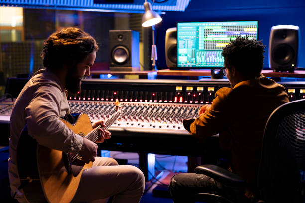 istock Musician records electro acoustic guitar sounds with technician in studio 2148357903