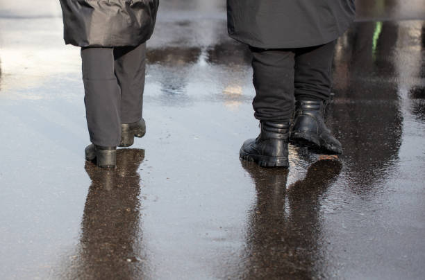 istock A man and a woman are walking through a puddle on a cold winter day 2148358365